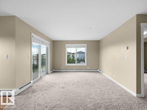 Carpeted living space with neutral painted walls and white baseboards - 216 5390 Chappelle Road, Edmonton, AB - Indoor Photo Showing Other Room