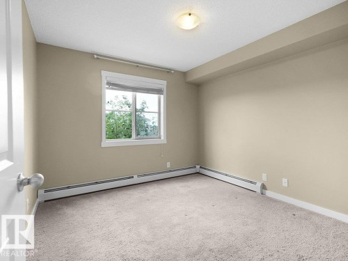 Neutral-toned room with plush carpeting and a large window - 216 5390 Chappelle Road, Edmonton, AB - Indoor Photo Showing Other Room