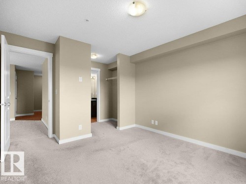 Spacious room featuring light-toned carpeting and neutral wall paint - 216 5390 Chappelle Road, Edmonton, AB - Indoor Photo Showing Other Room
