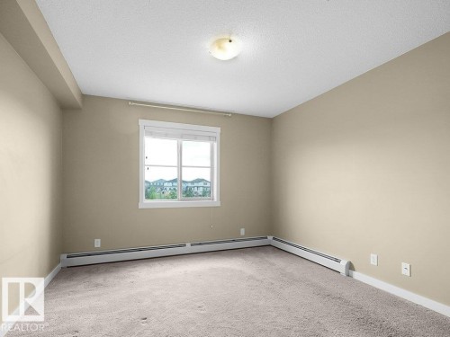 Carpeted interior room featuring neutral wall paint, white baseboards, and a window with white trim - 216 5390 Chappelle Road, Edmonton, AB - Indoor Photo Showing Other Room