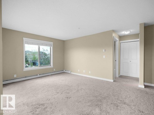 Spacious room featuring neutral carpeting and light beige wall paint - 216 5390 Chappelle Road, Edmonton, AB - Indoor Photo Showing Other Room