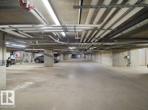 Underground parking garage featuring concrete flooring and structural columns - 216 5390 Chappelle Road, Edmonton, AB - Indoor Photo Showing Garage