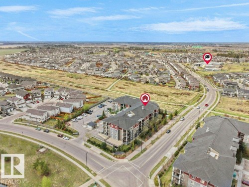 Aerial perspective showcasing a multi-story residential building with red and grey exterior siding - 216 5390 Chappelle Road, Edmonton, AB - Outdoor With View