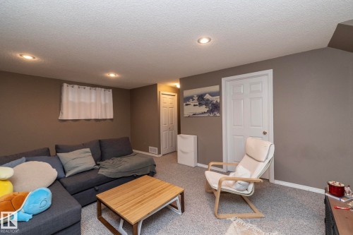 Carpeted lower-level room featuring recessed lighting, a window with white curtains, a white paneled door, and neutral-toned walls - 9112 166 Avenue, Edmonton, AB - Indoor