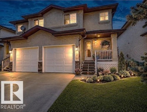 Stucco exterior featuring a two-car garage, concrete driveway, front porch with white railing, and decorative landscaping with integrated lighting - 9112 166 Avenue, Edmonton, AB - Outdoor With Deck Patio Veranda