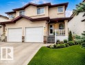 Stucco exterior featuring a covered front porch, dual garage doors, and a concrete driveway - 9112 166 Avenue, Edmonton, AB  - Outdoor With Deck Patio Veranda With Facade 