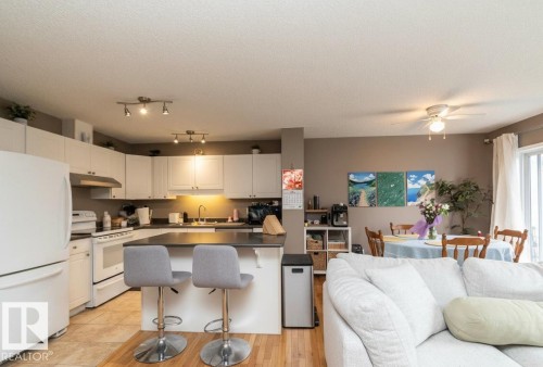 Open-concept kitchen featuring white cabinetry, track lighting, and a dark countertop island with seating - 9112 166 Avenue, Edmonton, AB - Indoor Photo Showing Kitchen