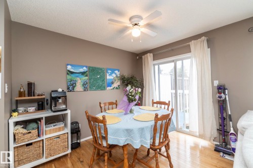 Dining area featuring wood-finish flooring, a ceiling fan with integrated lighting, and a sliding glass door providing access to an outdoor deck - 9112 166 Avenue, Edmonton, AB - Indoor Photo Showing Dining Room