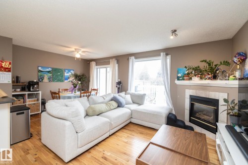 Open-concept living area featuring wood-finish flooring, a built-in fireplace with tile surround, and a ceiling fan - 9112 166 Avenue, Edmonton, AB - Indoor Photo Showing Living Room With Fireplace