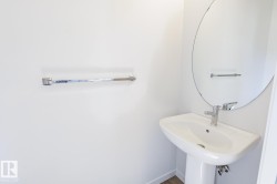 Pedestal sink with chrome faucet, complemented by a large oval mirror and chrome towel bar - 