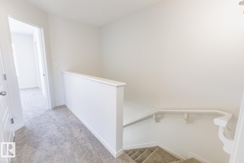 Upper-level landing featuring light gray carpet flooring and white painted walls - 3613 Triomphe Boulevard N, Beaumont, AB - Indoor Photo Showing Other Room