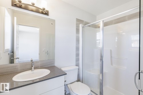 Contemporary bathroom featuring a spacious glass-enclosed shower, single vanity with a gray stone countertop, and a large wall-mounted mirror - 3613 Triomphe Boulevard N, Beaumont, AB - Indoor Photo Showing Bathroom