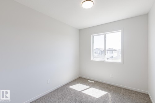 Room featuring a double-pane window, flush-mount ceiling light, light gray wall paint, and gray carpet flooring - 3613 Triomphe Boulevard N, Beaumont, AB - Indoor Photo Showing Other Room