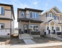 Modern two-story home featuring a covered front entry with columns, a dark front door, and a combination of horizontal siding and stone veneer accents - 3613 Triomphe Boulevard N, Beaumont, AB  - Outdoor With Facade 