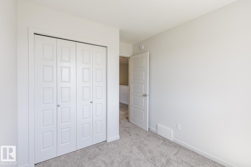 Bedroom featuring light grey carpeting, white walls, and white trim - 3613 Triomphe Boulevard N, Beaumont, AB - Indoor