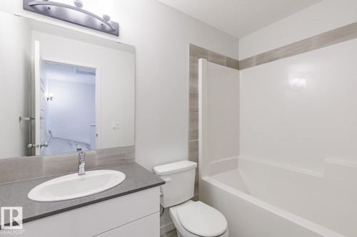 Contemporary bathroom featuring a combined tub and shower unit, a spacious vanity with a gray countertop, an oval undermount sink, and a wall-mounted light fixture - 3613 Triomphe Boulevard N, Beaumont, AB - Indoor Photo Showing Bathroom