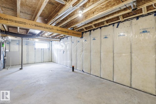 Unfinished basement with exposed ceiling joists and subfloor, insulated walls, and a concrete floor - 3613 Triomphe Boulevard N, Beaumont, AB - Indoor Photo Showing Basement