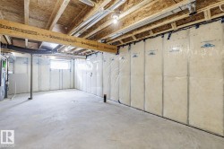 Unfinished basement with exposed ceiling joists and subfloor, insulated walls, and a concrete floor - 