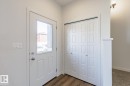 Entryway featuring a white door with a clear glass insert, wood-finish flooring, and a bifold closet with panel detailing - 3613 Triomphe Boulevard N, Beaumont, AB  - Indoor Photo Showing Other Room 