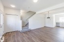 Open concept living space featuring wood-finish flooring, a carpeted staircase, and contemporary lighting fixtures - 3613 Triomphe Boulevard N, Beaumont, AB  - Indoor Photo Showing Other Room 