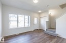 Bright living space featuring wood-finish flooring, a large multi-pane window, a white entry door with glass insert, bi-fold closet doors, and carpeted stairs - 3613 Triomphe Boulevard N, Beaumont, AB  - Indoor Photo Showing Other Room 
