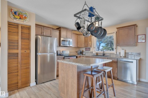 Kitchen featuring wood-finish flooring, wood cabinetry, granite-finish countertops, stainless steel appliances, and a tile backsplash - 112 Oak Drive, Wetaskiwin, AB - Indoor Photo Showing Kitchen
