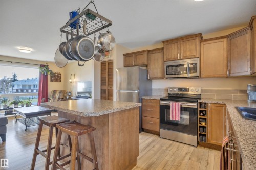 Kitchen featuring wood-finish flooring, light wood cabinetry, stainless steel appliances, granite-style countertops, and a subway tile backsplash - 112 Oak Drive, Wetaskiwin, AB - Indoor Photo Showing Kitchen With Double Sink