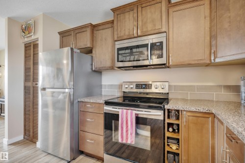 Kitchen featuring light wood cabinetry with crown molding, stainless steel appliances, granite-look countertops, and a subway tile backsplash - 112 Oak Drive, Wetaskiwin, AB - Indoor Photo Showing Kitchen
