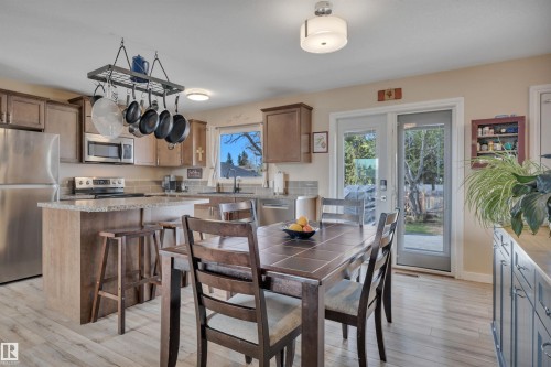 Kitchen featuring wood-finish flooring, light wood cabinetry, stone countertops, and a tile backsplash - 112 Oak Drive, Wetaskiwin, AB - Indoor Photo Showing Dining Room