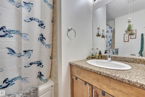 Bathroom featuring a wood-finish vanity with an integrated oval sink, a speckled countertop, and a chrome faucet - 112 Oak Drive, Wetaskiwin, AB - Indoor Photo Showing Bathroom
