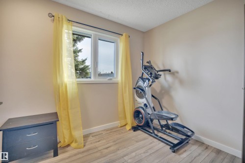 Room featuring light neutral wall paint, wood-finish flooring, white baseboards, and a white framed window - 112 Oak Drive, Wetaskiwin, AB - Indoor Photo Showing Gym Room