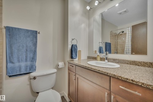 Bathroom featuring a granite-style countertop, integrated oval sink, wood-finish vanity with storage, and a large wall-mounted mirror - 112 Oak Drive, Wetaskiwin, AB - Indoor Photo Showing Bathroom