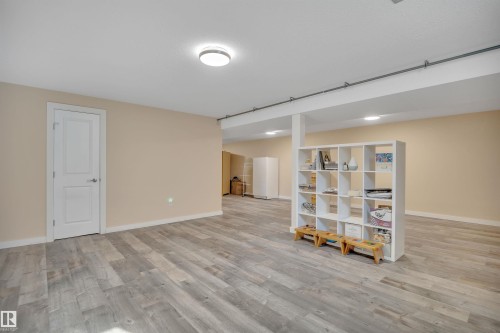 Spacious room featuring wood-finish flooring, neutral-toned walls, recessed lighting, and a white interior door - 112 Oak Drive, Wetaskiwin, AB - Indoor Photo Showing Other Room