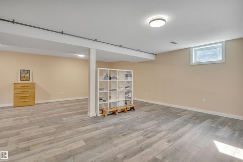 Spacious room featuring wood-finish flooring, neutral-toned walls, recessed lighting, and an egress window - 112 Oak Drive, Wetaskiwin, AB - Indoor
