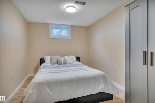 Bedroom featuring wood-finish flooring, white baseboards, a single window, recessed lighting, and a built-in wardrobe with panel doors and horizontal pulls - 112 Oak Drive, Wetaskiwin, AB - Indoor Photo Showing Bedroom