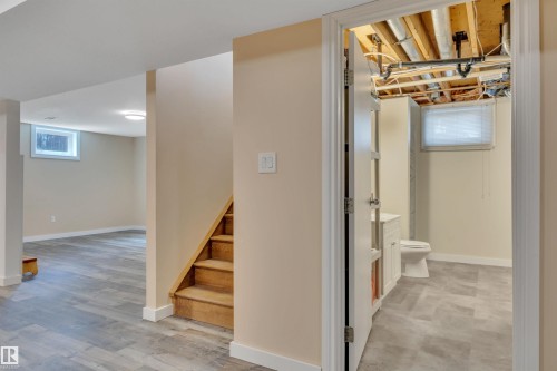 Finished lower level featuring wood-finish flooring, light neutral wall tones, and a wood staircase with carpeted treads - 112 Oak Drive, Wetaskiwin, AB - Indoor