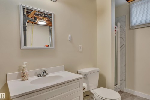 Bathroom featuring a white vanity with integrated sink, chrome faucet, wall-mounted mirror, and a toilet - 112 Oak Drive, Wetaskiwin, AB - Indoor Photo Showing Bathroom