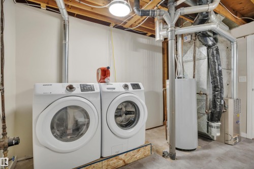 Laundry area featuring a front-loading washer and dryer set, water heater, and furnace - 112 Oak Drive, Wetaskiwin, AB - Indoor Photo Showing Laundry Room