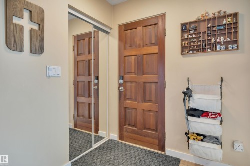 Recessed paneled door with a digital lock, mirrored closet doors, neutral wall tones, and a dark textured entryway mat - 112 Oak Drive, Wetaskiwin, AB - Indoor Photo Showing Other Room