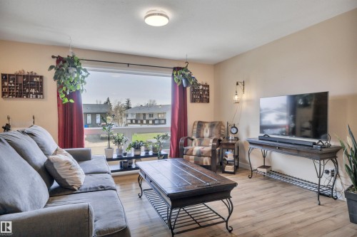 Living area featuring a large picture window, wood-finish flooring, and neutral wall tones - 112 Oak Drive, Wetaskiwin, AB - Indoor Photo Showing Living Room