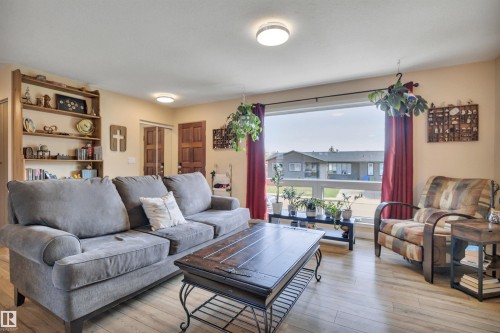 Spacious living area featuring a large window, recessed lighting, wood-finish flooring, and built-in shelving - 112 Oak Drive, Wetaskiwin, AB - Indoor Photo Showing Living Room