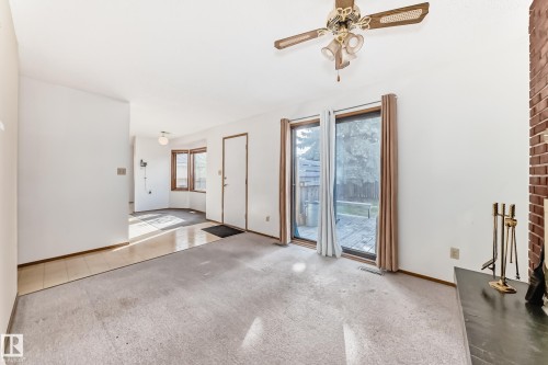 Living area featuring a brick fireplace, ceiling fan, and sliding glass doors opening to an outdoor deck - 9528 189 Street, Edmonton, AB - Indoor Photo Showing Other Room