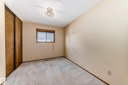 Carpeted room featuring a window with horizontal blinds, wood-finish trim, and an overhead light fixture - 9528 189 Street, Edmonton, AB - Indoor Photo Showing Other Room