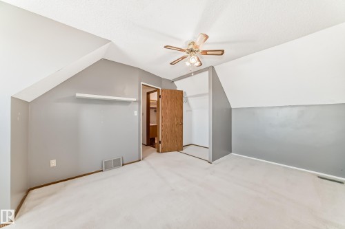 Carpeted room featuring a sloped ceiling, two-tone wall paint, a built-in shelf, and a ceiling fan with light - 9528 189 Street, Edmonton, AB - Indoor Photo Showing Other Room