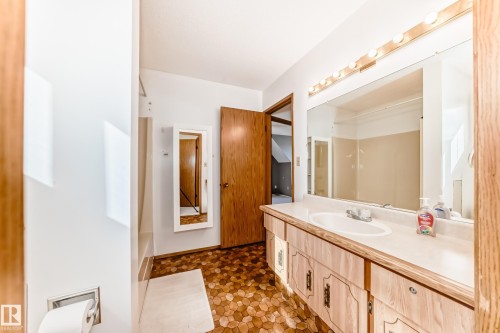 Bathroom featuring a vanity with a laminate countertop and integrated sink, a large wall-mounted mirror, and a multi-bulb light fixture - 9528 189 Street, Edmonton, AB - Indoor Photo Showing Bathroom