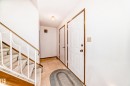 Entryway featuring a paneled door with brass hardware, tile flooring, and a carpeted staircase with a decorative metal railing and wood-finish trim - 9528 189 Street, Edmonton, AB  - Indoor Photo Showing Other Room 