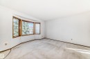 Bright room featuring a large bay window with wood-finish trim, white walls, and light-toned carpeting - 9528 189 Street, Edmonton, AB  - Indoor Photo Showing Other Room 