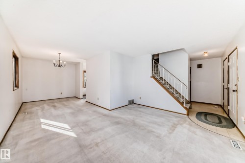 Open-concept living space featuring light-toned carpeting, white wall finishes, and dark wood trim - 9528 189 Street, Edmonton, AB - Indoor Photo Showing Other Room