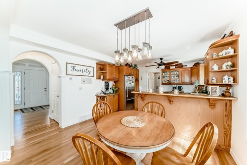 Dining area featuring wood-finish flooring and a round wooden table with seating - 11115 44 Street, Edmonton, AB - Indoor Photo Showing Dining Room