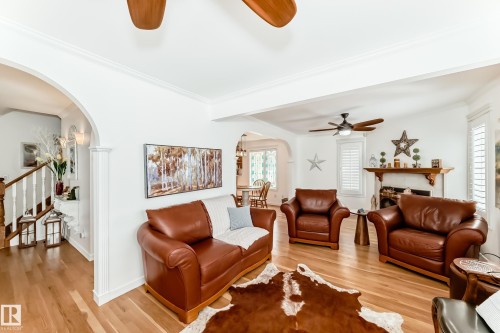 Living area featuring wood-finish flooring, white crown molding, and a fireplace with a wood mantle - 11115 44 Street, Edmonton, AB - Indoor Photo Showing Living Room